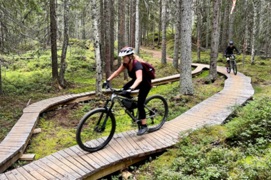 Bild till nyhetsinlägg om Stigcyklingens 5 spelregler. Två cyklister på en träbana i en skog.