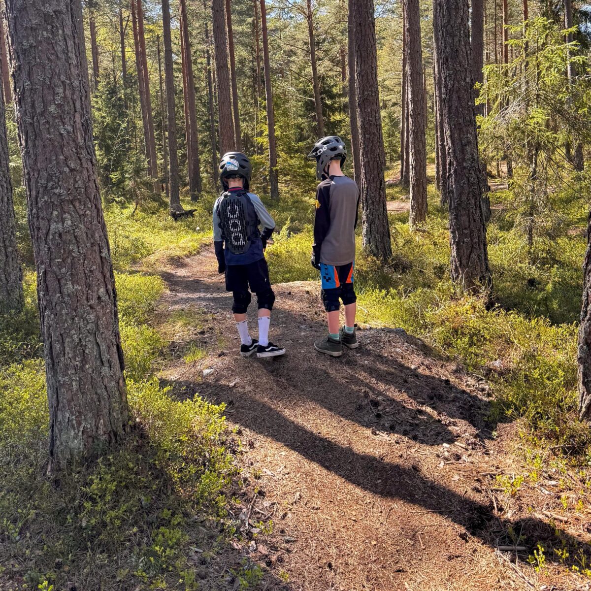 Två unga cyklister inspekterar banan i skogen.